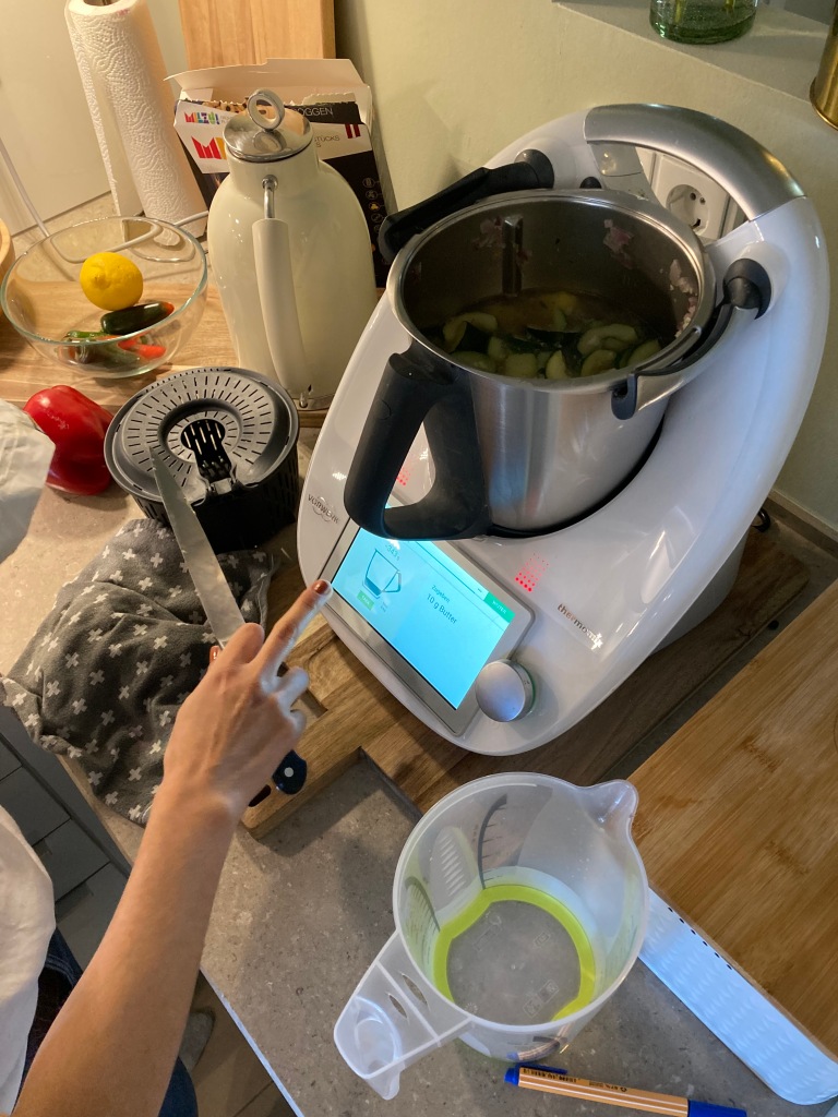 Hand mit Messer berührt Display einer digitalen Küchenmaschine